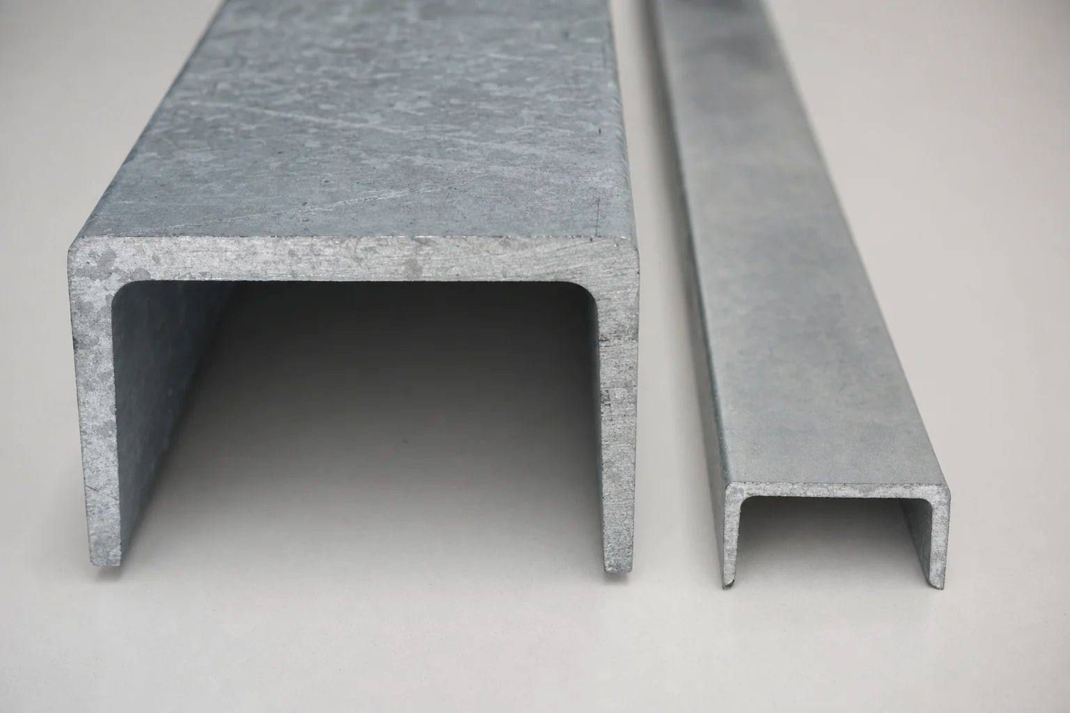 Premium thick hot-dip galvanised Australian-made structural steel section laid against a thinner imported steel section on a clean neutral surface